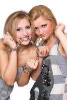 Two playful young women bound a chain photo