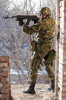 Soldier standing near wall with a gun photo