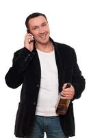 hombre sonriente con un teléfono y una botella de whisky escocés foto