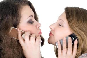 Two beautiful girls with phones. Isolated on white photo