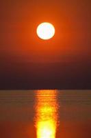 puesta de sol roja sobre la superficie del mar foto