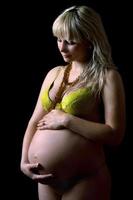 Young pregnant woman in yellow lingerie. Isolated photo