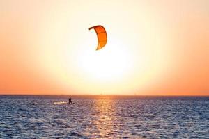 silueta de un kitesurfista en un golfo al atardecer foto