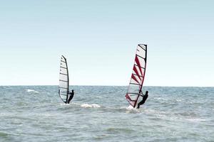 Two windsurfers on waves of a sea photo