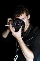 el joven - fotógrafo detrás del trabajo. aislado en un fondo negro 2 foto