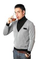 Young man drinking whiskey from a glass. Isolated photo