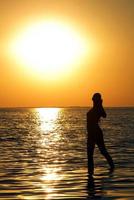 Silhouette of the young woman on a bay on a sunset photo