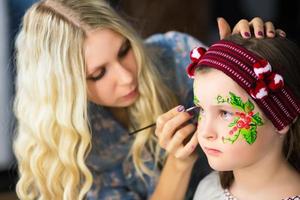 mujer pintando la cara de una niña foto