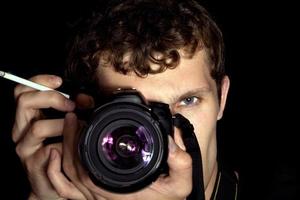 el joven - fotógrafo detrás del trabajo. aislado en un fondo negro 4 foto