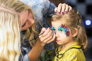 mujer pintando la cara de una niña foto