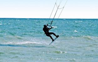 Silhouette of a kitesurfer on waves of a sea photo