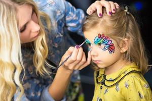 Visagist painting the face of a little girl photo