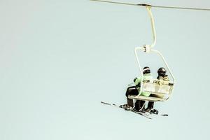 Low angle shot of a ski lift at ski resort with tow male skier friends in Gudauri in the mountains on a sunny winter day. Blue sky cinematic image. Extreme sport recreation concept photo