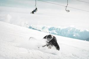 snowboarder is riding with snowboard from powder snow hill very fast and fall down photo