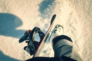 Traveler snowboarder on mountain peak, POV view on great winter mountains above the cloud and hiking boots. Legs of close up on background of snowy slope landscape photo