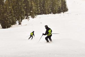 los esquiadores de la policía de esquí van cuesta abajo. control de pendientes vacaciones de trabajo de esquí. foto