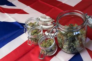 Cannabis buds in jars on UK United Kingdom national flag background. Marijuana business in Great Britain photo