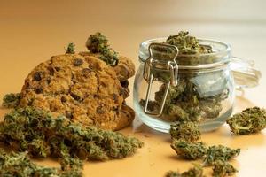 Cannabis product with oat cookie. THC weed buds background. Medical drug use, healthcare concept. Cookie with marijuana photo