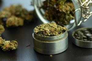 Grinder with marijuana close up. Cannabis use in healthcare. Blurry background with weed buds