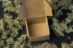 Empty open brown box on cannabis background top view photo