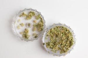 Grinder full of marijuana top view on white background. Isolated cannabis, design template photo