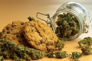 Oat cookie with cannabis buds close-up. Medical marijuana product concept. THC use in healthcare. Jar with weed photo