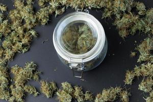 Jar with cannabis on background with marijuana buds top view. Weed business concept photo