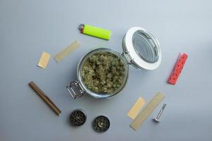 vista superior de las cosas para fumar cannabis. marihuana y papel sobre fondo gris foto