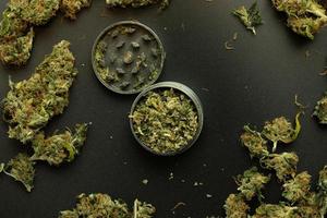 Flat lay with cannabis, marijuana and weed. Top view on grinder, black background. THC illustration photo