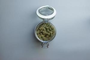 Medical marijuana stored in jar on gray background top view with copy space photo