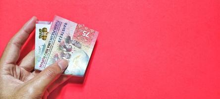 Man holding Indonesian 75,000 rupiah banknote, latest issue photo