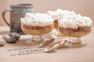 Three individual servings of an apple compote dessert and three silver spoons. photo