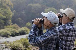 los niños asiáticos están usando binoculares para observar pájaros y peces en el parque nacional local durante el campamento de verano, idea para aprender criaturas y animales salvajes e insectos fuera del aula. foto