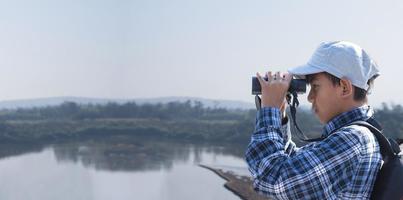 niños asiáticos que usan binoculares para observar pájaros en los árboles y peces en el río en el parque nacional local durante el campamento de verano, idea para aprender criaturas y animales salvajes e insectos fuera del aula. foto