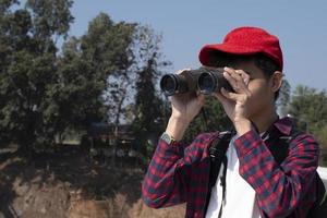 Asian boys using binoculars to watch birds on trees and fish in river in local national park during summer camp, idea for learning creatures and wildlife animals and insects outside the classroom. photo