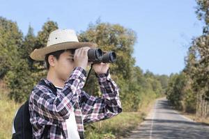 Asian boys using binoculars to watch birds on trees and fish in river in local national park during summer camp, idea for learning creatures and wildlife animals and insects outside the classroom. photo