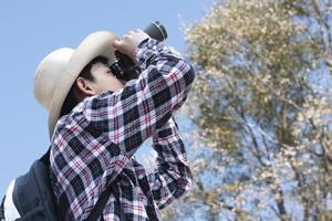 Asian boys using binoculars to watch birds on trees and fish in river in local national park during summer camp, idea for learning creatures and wildlife animals and insects outside the classroom. photo