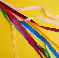 many silk multi-colored ribbons on a yellow background photo