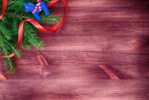 Green branch decorated with red ribbon on a wooden surface photo