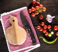 tabla de cortar y cuchillo de cocina, cerca de tomates cherry rojos maduros foto