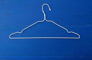 thin white metal hanger on a blue wooden background photo