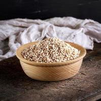 wheat grain in a wooden bowl on a brown table photo