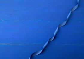 blue silk thin ribbon twisted on a blue wooden background photo