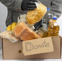 recoge alimentos, frutas y cosas en una caja de cartón para ayudar a los necesitados y los pobres foto