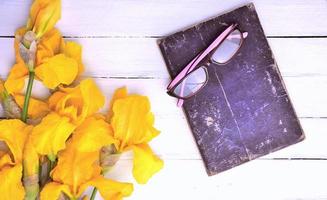 libro antiguo con gafas sobre un fondo blanco de madera foto