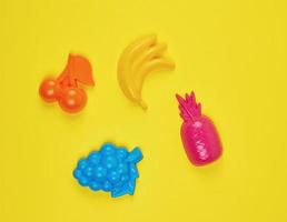 multicolored plastic toys fruits on a yellow  background photo
