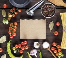 open notepad with brown sheets and ingredients for cooking pasta photo