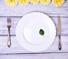 Empty white plate and metal fork and knife photo