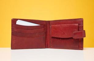 Open brown leather wallet with bank cards inside on a yellow background photo