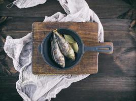 dos percas de pescado fresco con especias en una sartén negra de hierro fundido foto